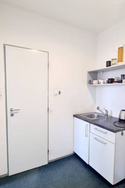Kleine Büroküche mit Spüle, Regal und Wasserkocher.