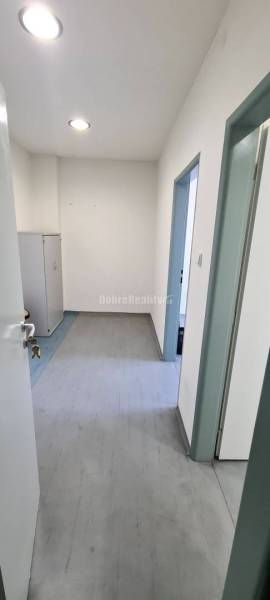 Innenraum eines Büros mit weißen Wänden, abschließbarem Schrank und Boden in Holzoptik.