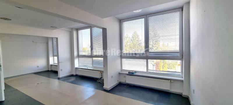 Ein geräumiges Büro mit großen Fenstern und einem Boden in Holzoptik.