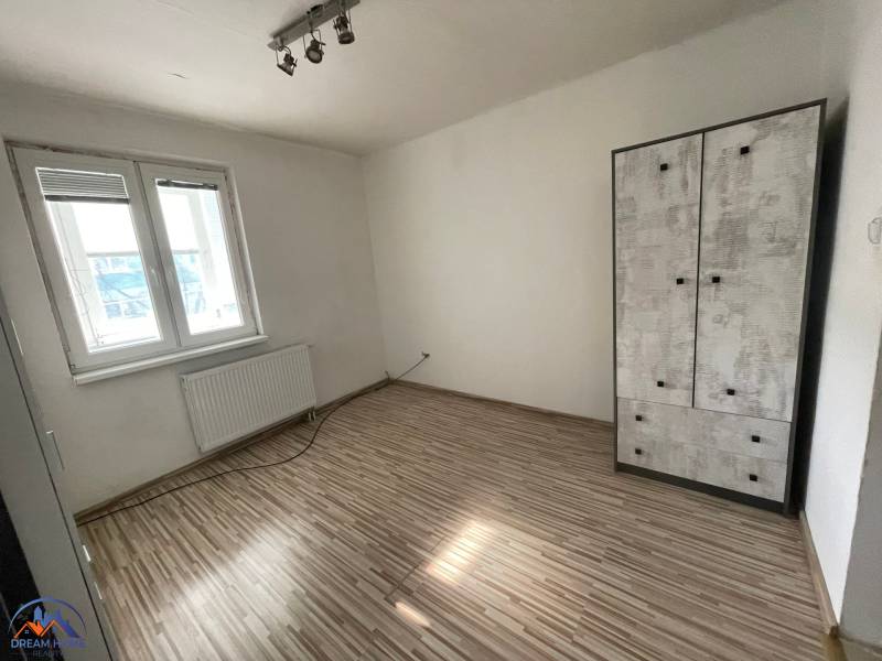 Ein Zimmer in einer 3-Zimmer-Wohnung mit einem Boden in Holzoptik und einfacher Einrichtung.