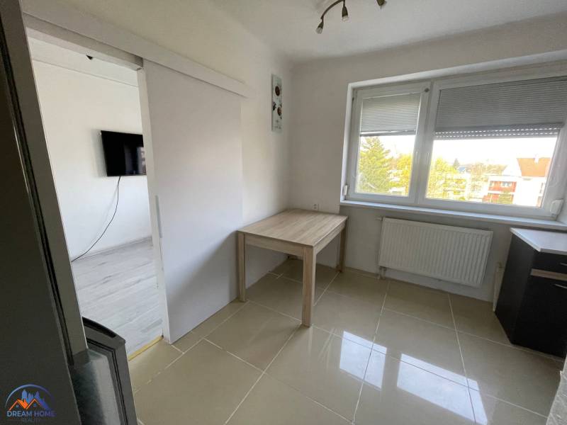 Izba v 3-izbovom byte s dlažbou, oknom a stolom.