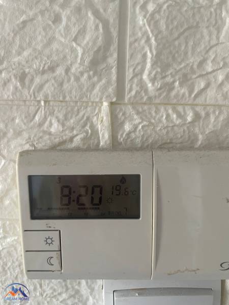 Ein Thermostat an der weißen Wand in einer 3-Zimmer-Wohnung zeigt 19,6 °C an.