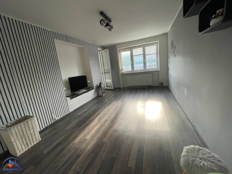 Wohnzimmer in einer 3-Zimmer-Wohnung mit Holzboden und Fernseher.