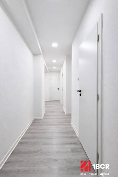 Ein Flur mit weißen Wänden und einem Boden in Holzoptik in einer 3-Zimmer-Wohnung.