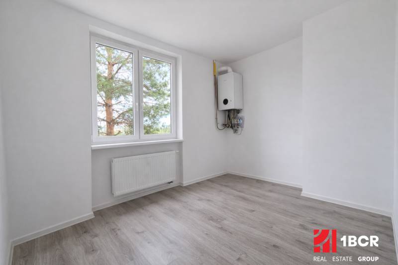 Ein Zimmer in einer 3-Zimmer-Wohnung mit einem Boden in Holzoptik und einem Heizkörper.