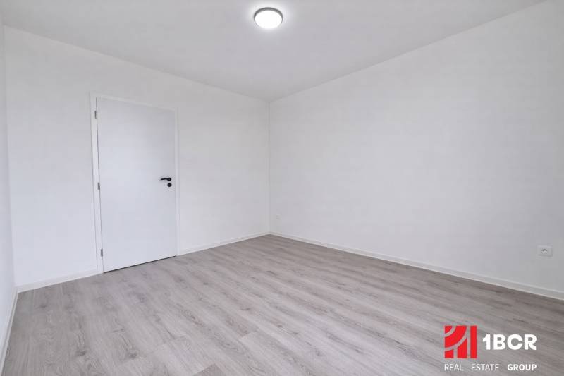Ein leerer Raum in einer 3-Zimmer-Wohnung mit Holzboden und weißen Wänden.