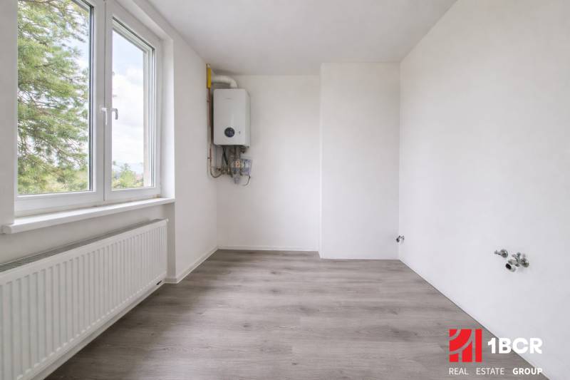 Ein Zimmer mit weißen Wänden und einem Holzboden in einer 3-Zimmer-Wohnung.