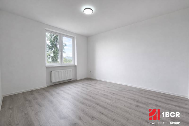 Geräumiges Zimmer mit Fenster und Holzboden in einer 3-Zimmer-Wohnung.