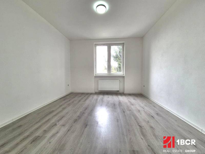 Ein leerer Raum mit Holzboden und weißen Wänden in einer 3-Zimmer-Wohnung.