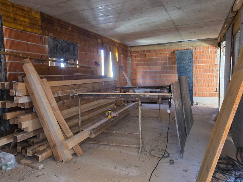 Baustelle einer 3-Zimmer-Wohnung mit unvollendeten Ziegelwänden und Holzbalken.