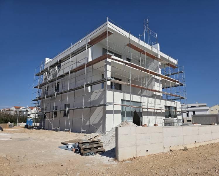 Ein Gebäude in SRIMA mit einem Gerüst, es wird an einer 3-Zimmer-Wohnung gearbeitet.