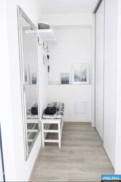 Eingangsbereich in einer 2-Zimmer-Wohnung mit Spiegel, Bank und Boden in Holzoptik.