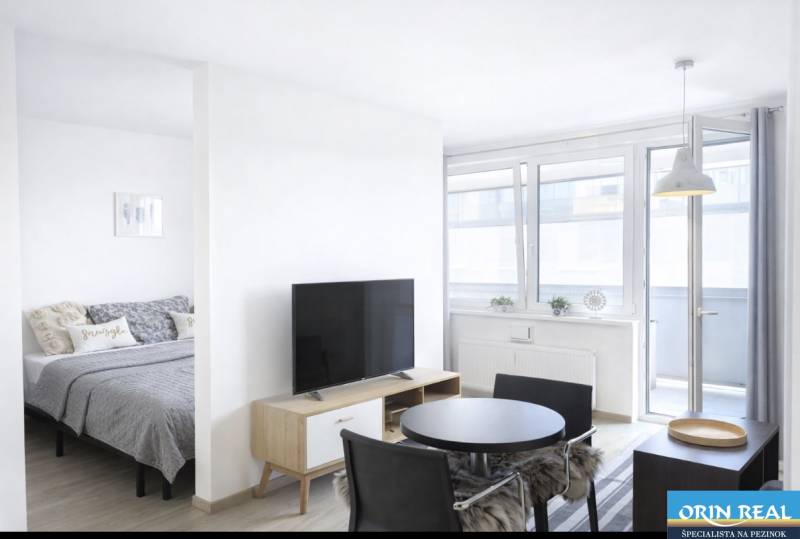 Helles Wohnzimmer in einer 2-Zimmer-Wohnung mit Fernseher und Esstisch.