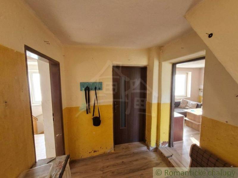 Innenraum eines Einfamilienhauses mit Holzboden, gelbe Wände, Kleiderständer, Sofa.