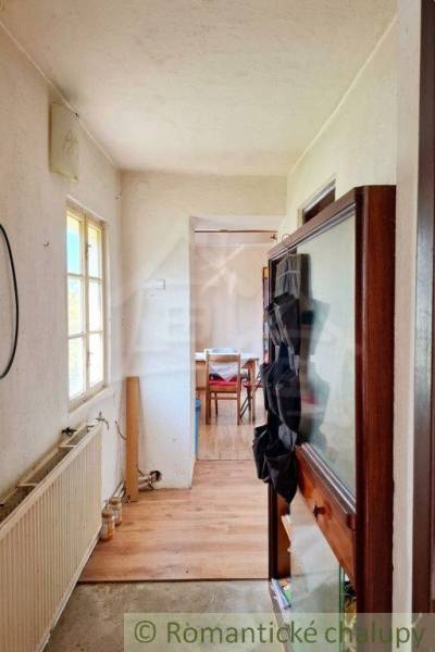 Interieur eines Einfamilienhauses mit einem schmalen Flur und einem Raum am Ende.