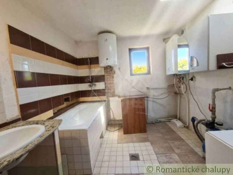 Badezimmer mit Fliesenboden und Badewanne in einem Einfamilienhaus.