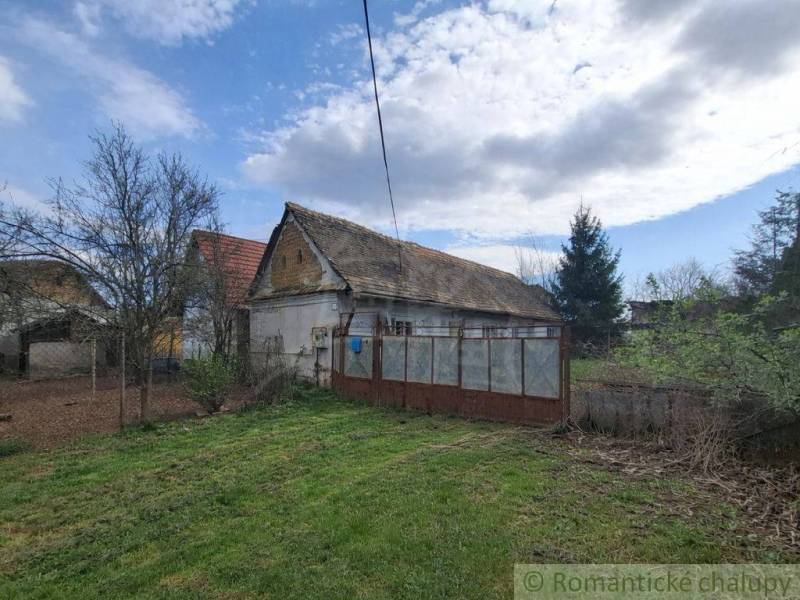 Ein Einfamilienhaus in Ozdín, umgeben von einem Garten und Bäumen, unter blauem Himmel.