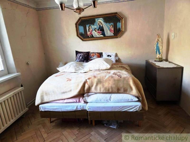 Ein Schlafzimmer in einem Einfamilienhaus mit einem Bett und religiöser Dekoration an der Wand.