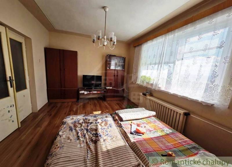 Ein Zimmer in einem Einfamilienhaus mit einem Bett, einem Schrank und einem Boden mit Holzdekor.