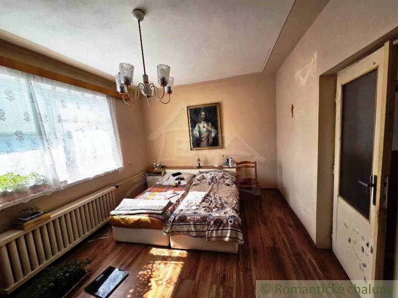 Schlafzimmer im Einfamilienhaus mit Bett, Kronleuchter, Bild und Boden mit Holzdekor.