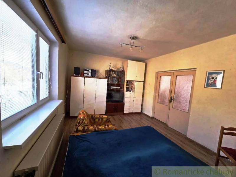 Ein Zimmer mit einem Holzboden, einem Bett, einem Schrank und einem dekorativen Bild in einem Einfamilienhaus.