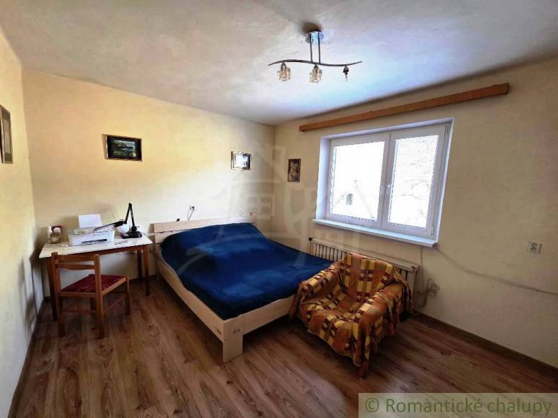 Schlafzimmer mit Bett, Tisch und Stuhl in einem Einfamilienhaus. Boden mit Holzdekor.