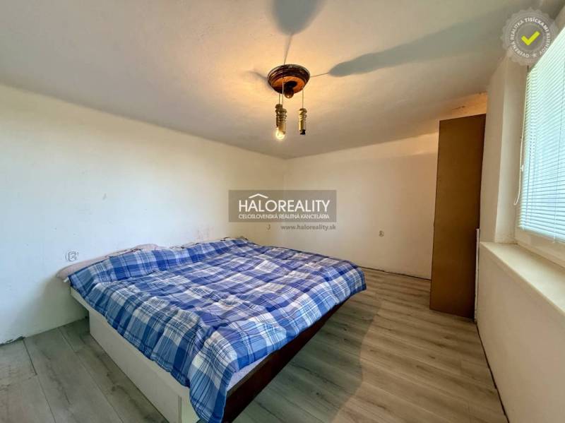 Ein ruhiges Schlafzimmer mit einem einfachen Bett und einem Boden in Holzoptik.