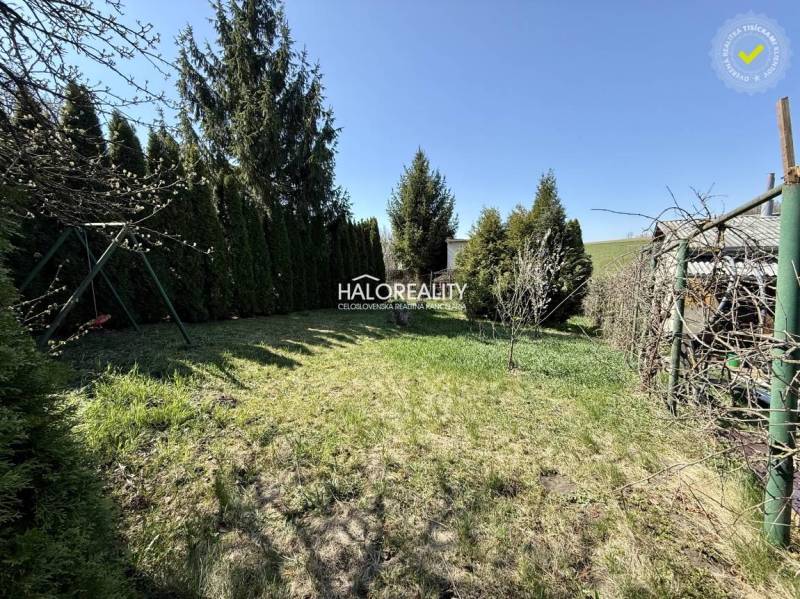 Die Gärten in Rimavská Sobota sind von Nadelbäumen und gepflegtem Rasen unter blauem Himmel umgeben.