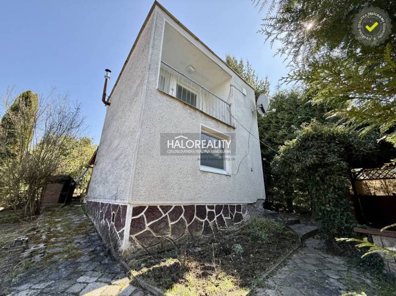 Ein Einfamilienhaus umgeben von Bäumen und Sträuchern in den Gärten der Stadt Rimavská Sobota.