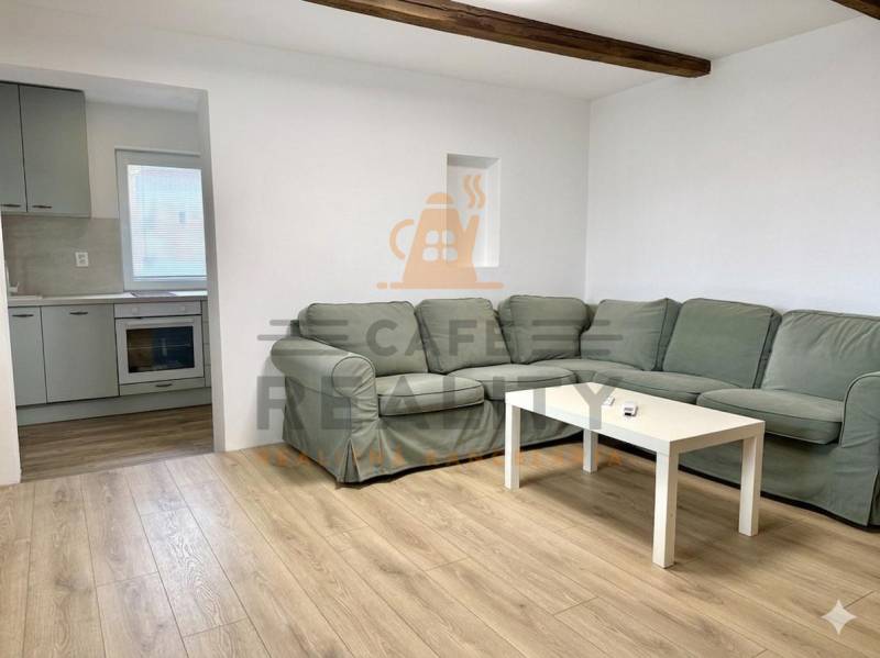 Wohnzimmer mit Ecksofa, Holzboden und Küche in einem Einfamilienhaus.