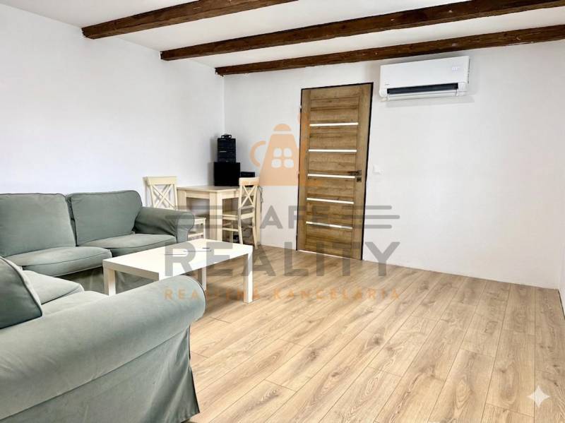 Wohnzimmer in einem Einfamilienhaus mit Holzbalken und einem Boden in Holzoptik.