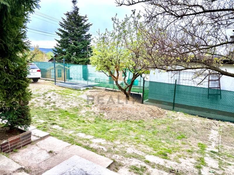 Ein Einfamilienhaus in Bratislava-Záhorská Bystrica, Podkerepušky mit einem grasbewachsenen Hof und Bäumen.