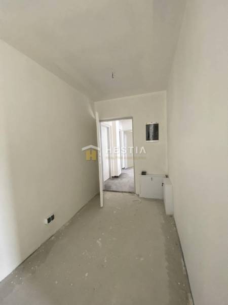 Der Flur in der 2-Zimmer-Wohnung mit weißen Wänden, Türen und einem Boden im Rohzustand.