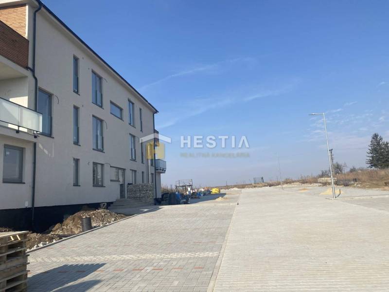 Neubau einer 3-Zimmer-Wohnung in Petrová Ves mit umliegender befestigter Straße und klarem Himmel.