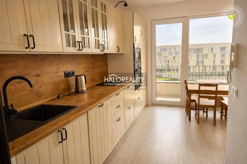 Küche mit Holzboden, weißen Schränken und Esstisch in einer 2-Zimmer-Wohnung.