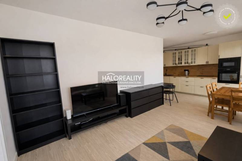 Wohnzimmer in einer Zweizimmerwohnung mit Küchenzeile und Holzboden.