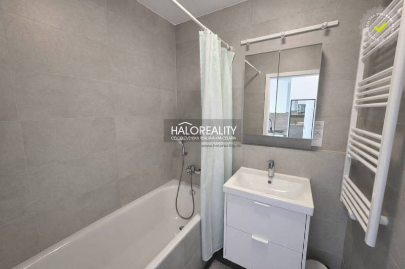 Badezimmer mit Badewanne, Waschbecken und Spiegel in einer 2-Zimmer-Wohnung.