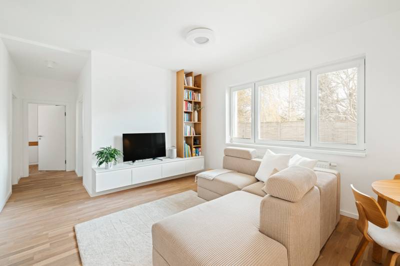 Helles Wohnzimmer in einer 4-Zimmer-Wohnung mit Holzboden, Sofa und Fernseher.