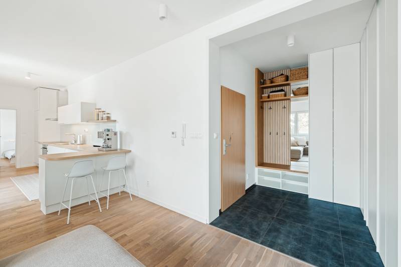 Eingangsflur in einer 4-Zimmer-Wohnung mit Holzboden und Küchenzeile.