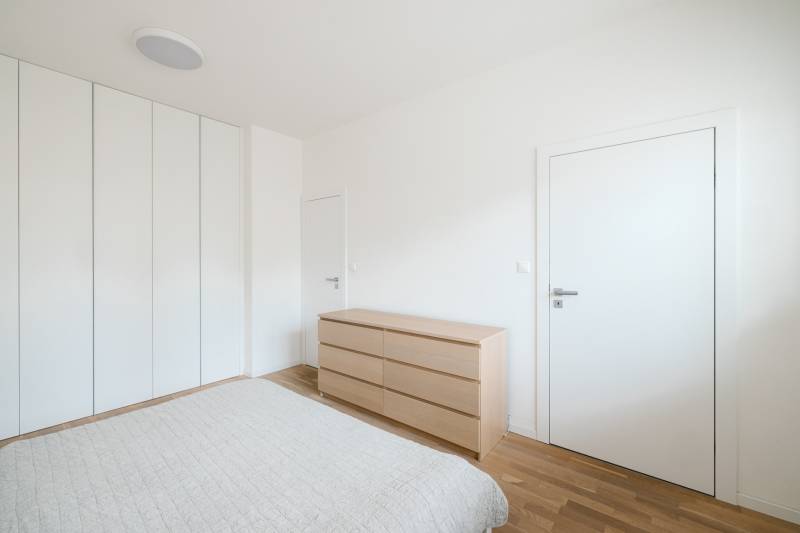 Schlafzimmer in einer 4-Zimmer-Wohnung mit weißen Wänden und einem Boden in Holzoptik.