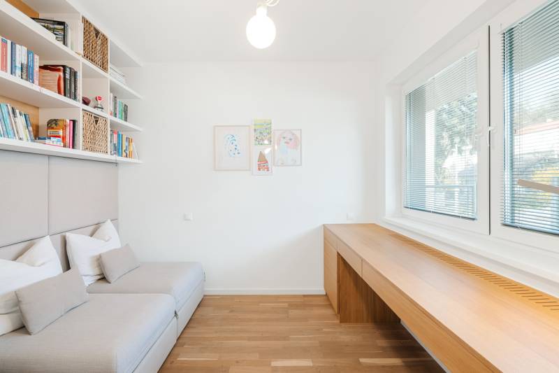 Helles Zimmer mit Holzboden, Sofa und großen Fenstern.