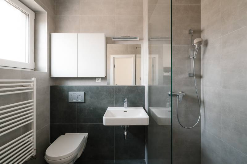 Badezimmer in einer 4-Zimmer-Wohnung mit Waschbecken, Dusche, WC und Schrank.