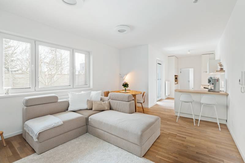 Helles Wohnzimmer mit Küchenzeile, Sofa und Holzboden.
