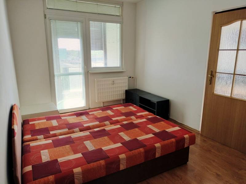 Schlafzimmer in einer 3-Zimmer-Wohnung mit einem Bett und einem Boden in Holzoptik.