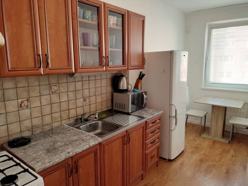 Küche in einer 3-Zimmer-Wohnung mit Holzboden und Holzmöbeln.