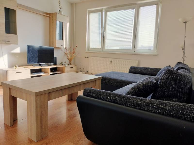 Wohnzimmer mit Sofa, Fernseher und Holzboden in einer 3-Zimmer-Wohnung.