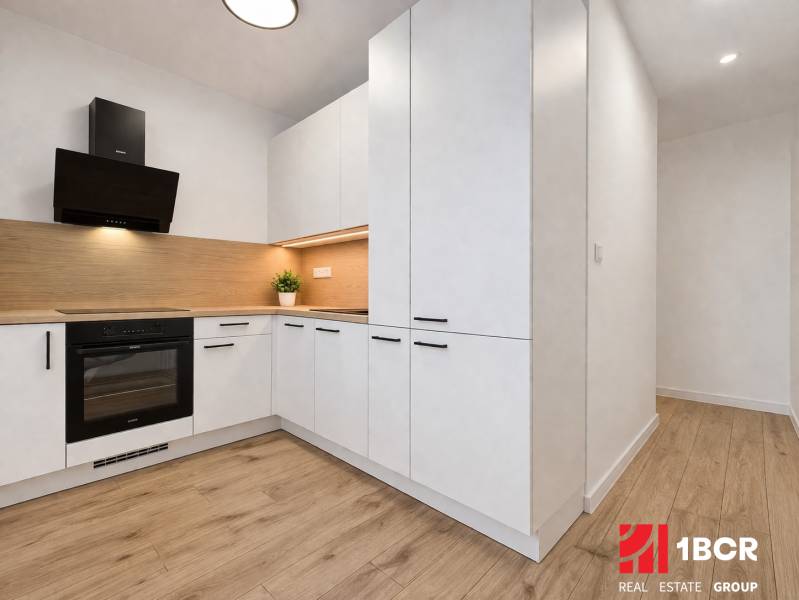 Küche mit hellen Möbeln und Boden in Holzoptik in einer 2-Zimmer-Wohnung.