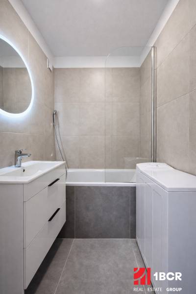 Badezimmer in einer 2-Zimmer-Wohnung mit Badewanne und Waschbecken mit Stauraum.