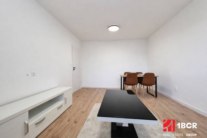 Ein Zimmer in einer 2-Zimmer-Wohnung mit einem Holzboden, einem Tisch und Stühlen.