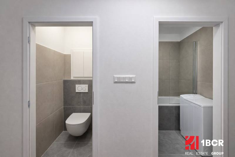 Fliesen im Badezimmer mit Waschmaschine und Toilette in einer 2-Zimmer-Wohnung.